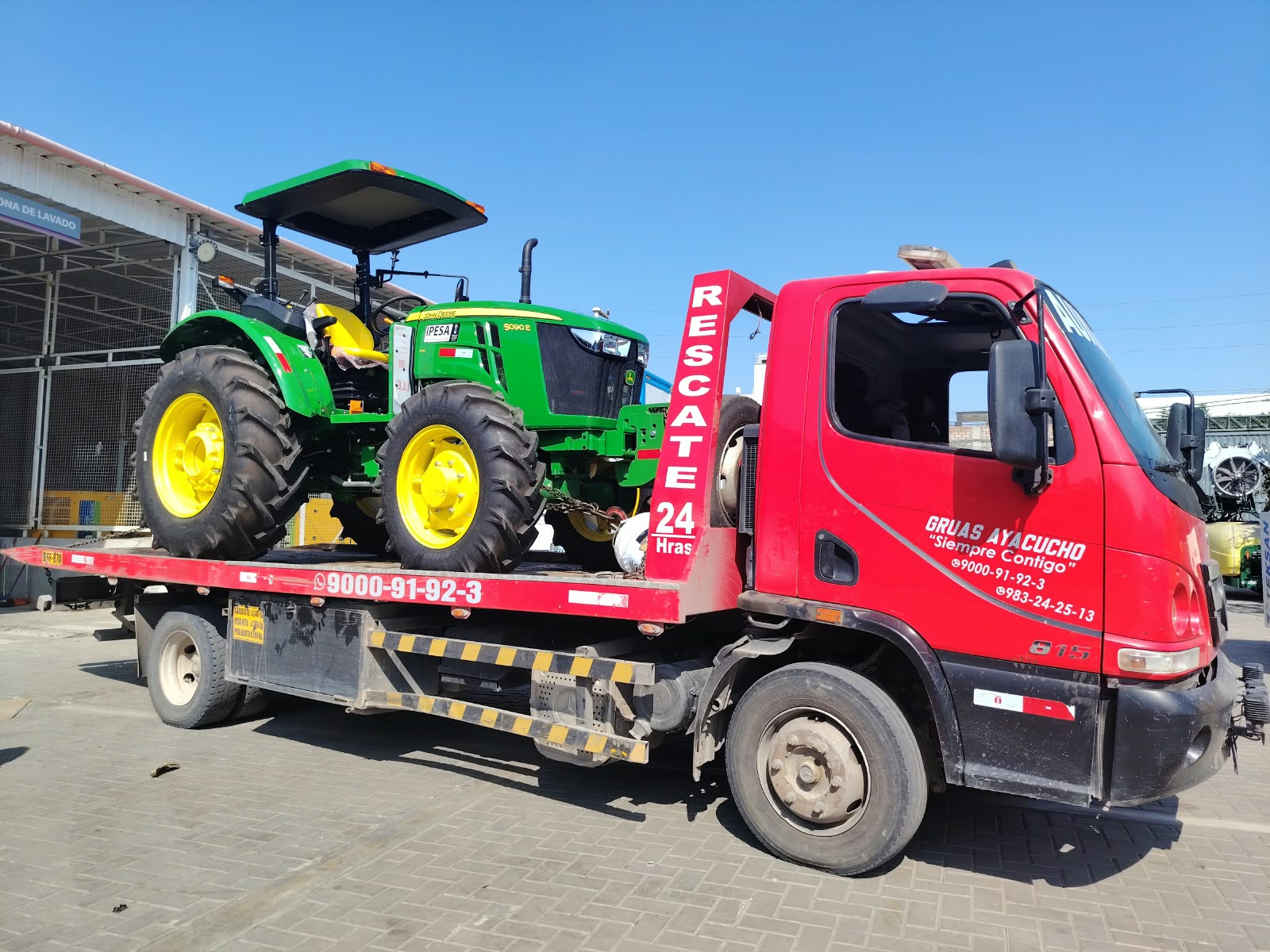 Tractor agrícola sobre la plataforma de la grúa roja